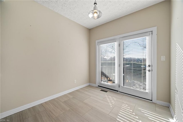 spare room with a textured ceiling and light tile patterned flooring