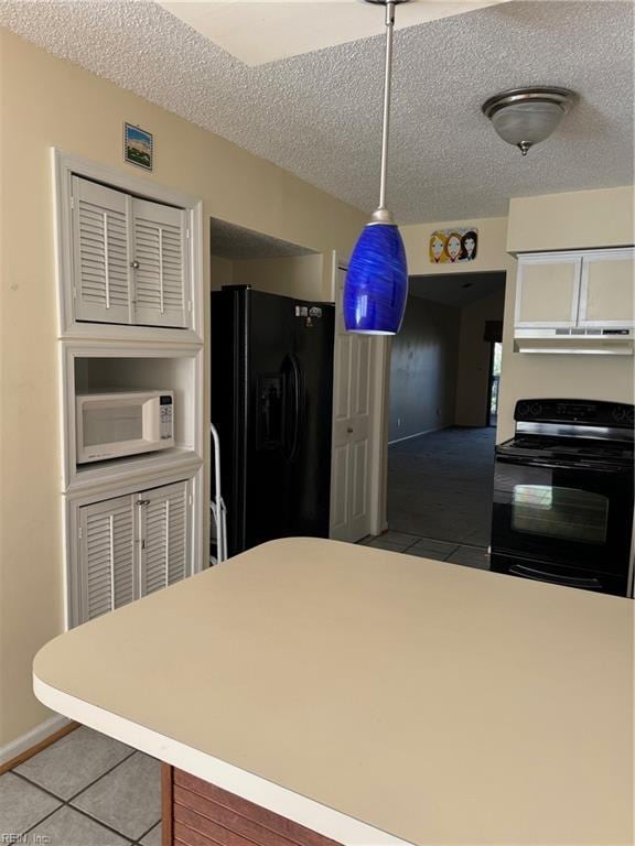 kitchen with tile patterned floors, hanging light fixtures, black appliances, and a textured ceiling