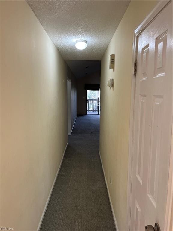 hall with dark colored carpet and a textured ceiling