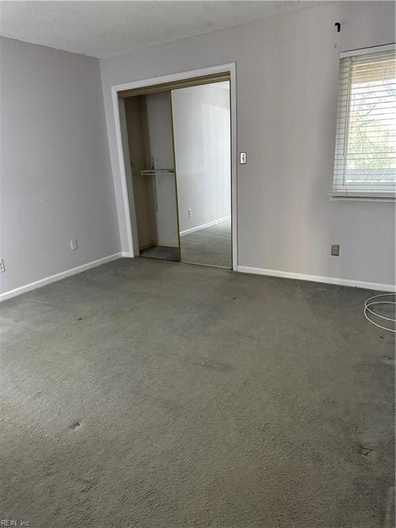 unfurnished bedroom featuring dark carpet and a closet