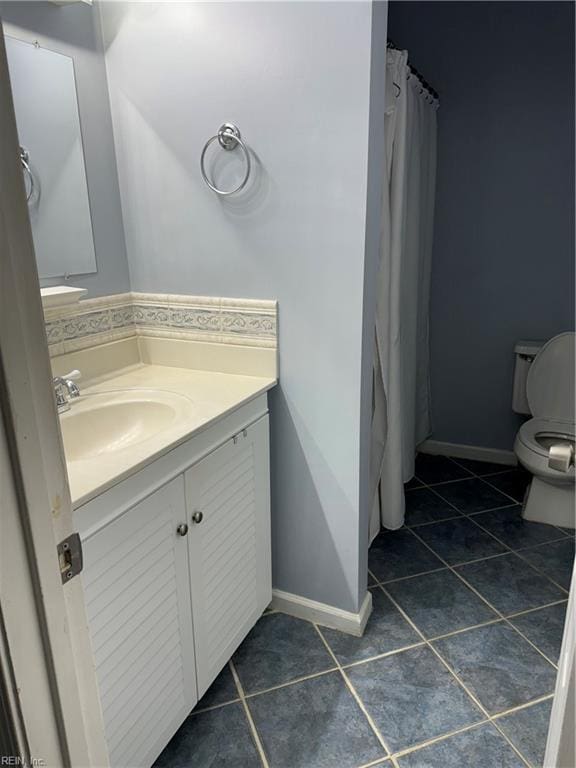 bathroom with toilet, vanity, and tile patterned floors