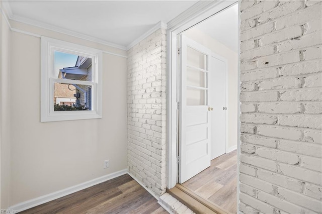 hall with hardwood / wood-style floors, ornamental molding, and brick wall