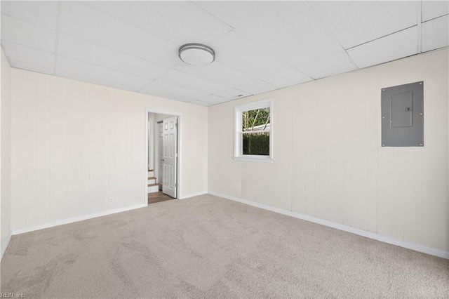 carpeted spare room featuring a drop ceiling and electric panel