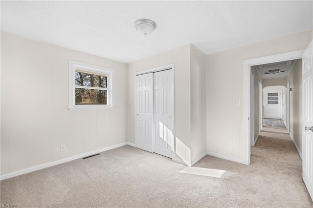 unfurnished bedroom featuring light carpet and a closet