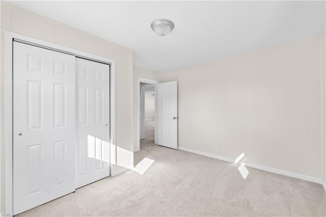 unfurnished bedroom with light colored carpet and a closet