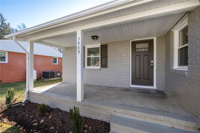 view of exterior entry featuring a porch and central AC