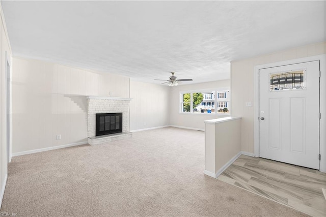 unfurnished living room featuring ceiling fan, light colored carpet, and a fireplace