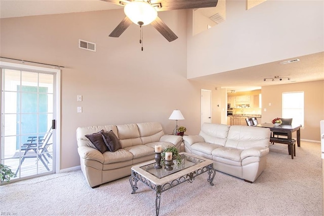 living room featuring ceiling fan, light colored carpet, and a high ceiling