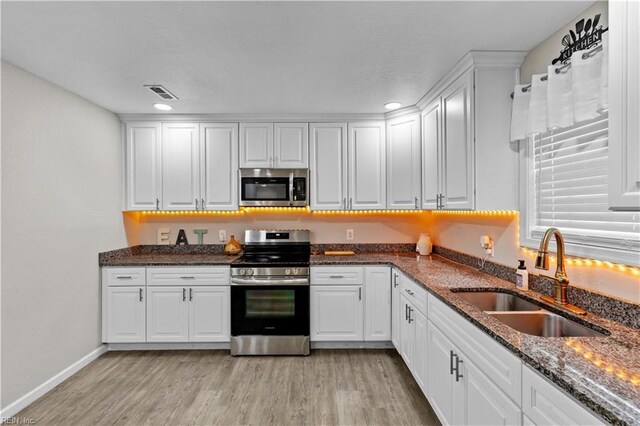 kitchen with white cabinetry, sink, stainless steel appliances, and light wood-type flooring