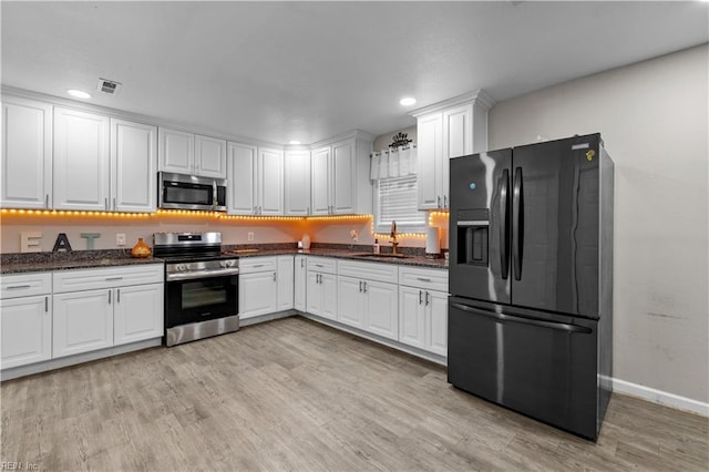 kitchen featuring sink, white cabinets, light wood-type flooring, and appliances with stainless steel finishes