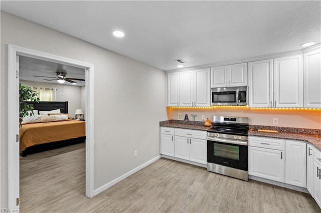 kitchen featuring white cabinetry, ceiling fan, stainless steel appliances, dark stone counters, and light wood-type flooring