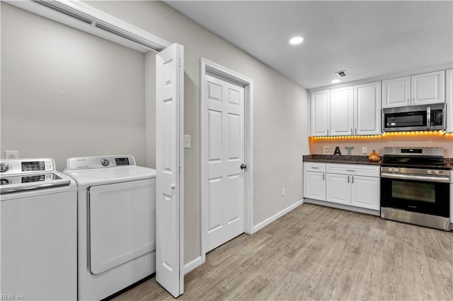 laundry area with light hardwood / wood-style flooring and washing machine and clothes dryer