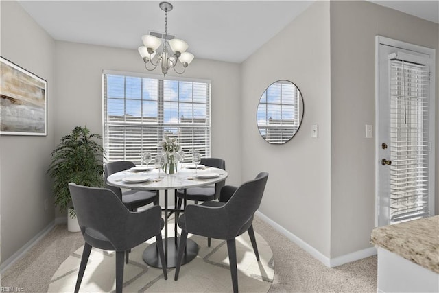 dining space with light carpet and an inviting chandelier