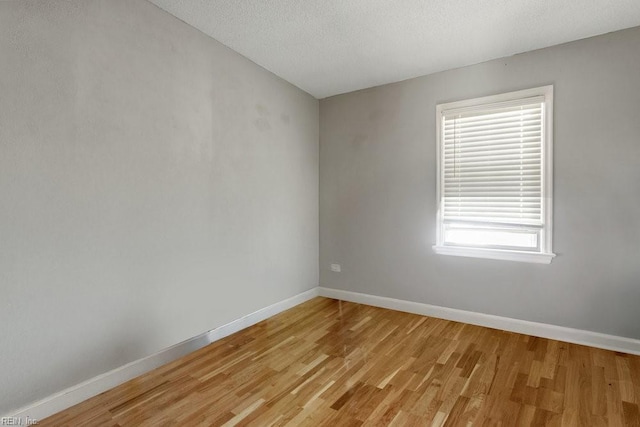 empty room with a textured ceiling and light hardwood / wood-style flooring