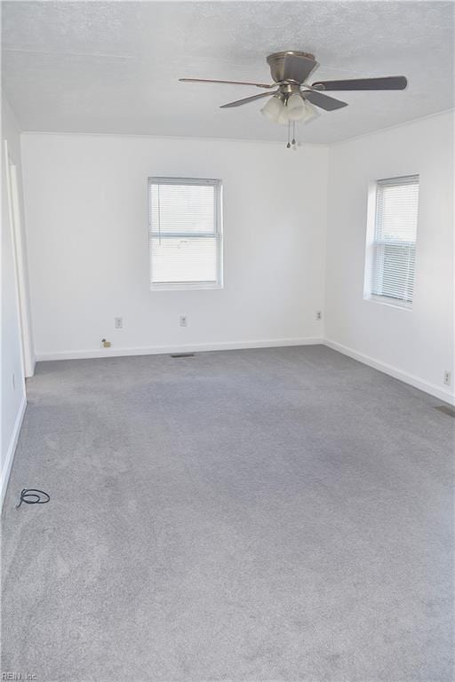 unfurnished room with a textured ceiling, dark carpet, and ceiling fan