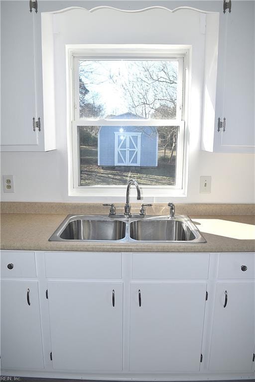 kitchen featuring a wealth of natural light, sink, and white cabinets