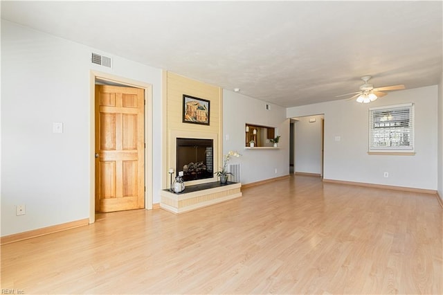 unfurnished living room with baseboards, visible vents, light wood finished floors, and a large fireplace