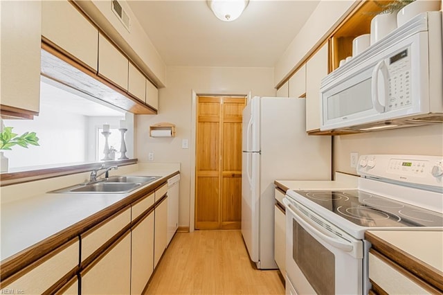 kitchen with visible vents, light wood-type flooring, light countertops, white appliances, and a sink