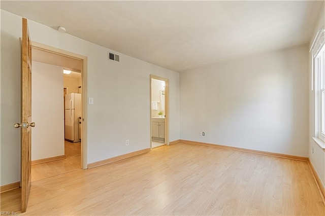 unfurnished bedroom featuring visible vents, light wood finished floors, baseboards, and freestanding refrigerator