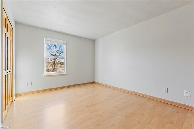 spare room featuring baseboards and light wood-style floors