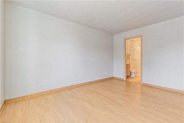 spare room featuring light wood-type flooring and baseboards