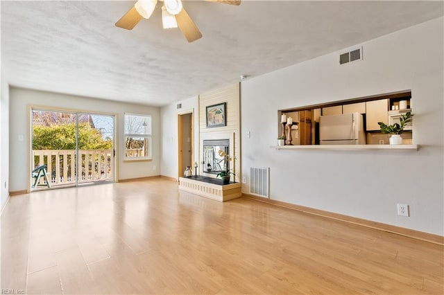 unfurnished living room featuring a multi sided fireplace, visible vents, and wood finished floors