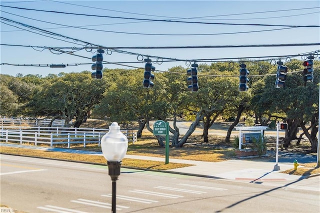 view of road with sidewalks, curbs, traffic signs, and traffic lights