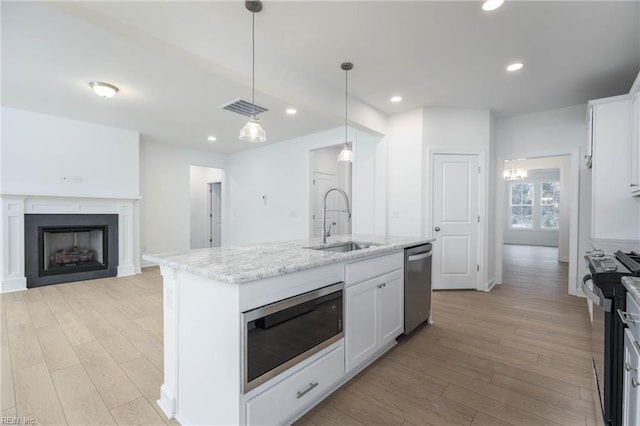 kitchen with white cabinetry, sink, hanging light fixtures, a kitchen island with sink, and appliances with stainless steel finishes