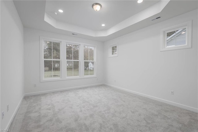 carpeted empty room featuring a tray ceiling