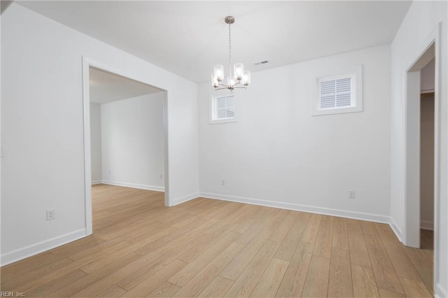 unfurnished room featuring a chandelier and light wood-type flooring