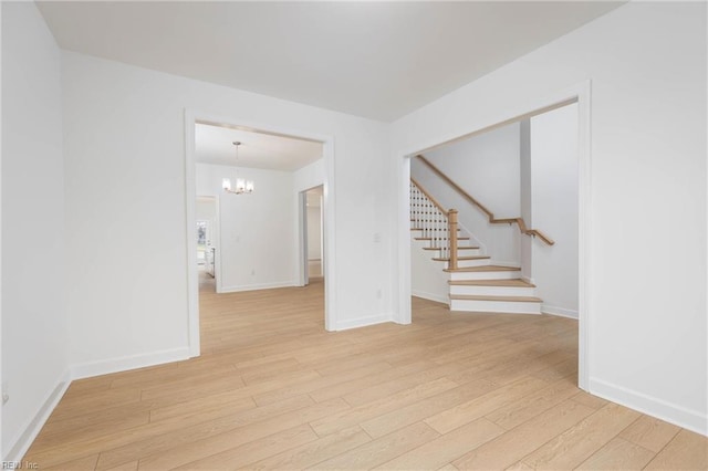 empty room with a chandelier and light wood-type flooring