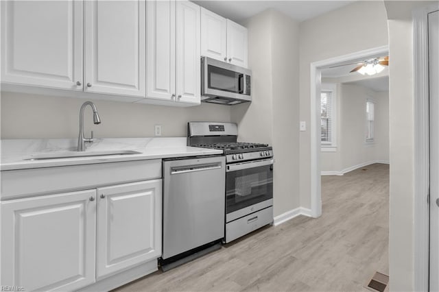 kitchen featuring white cabinets, sink, light hardwood / wood-style flooring, ceiling fan, and stainless steel appliances