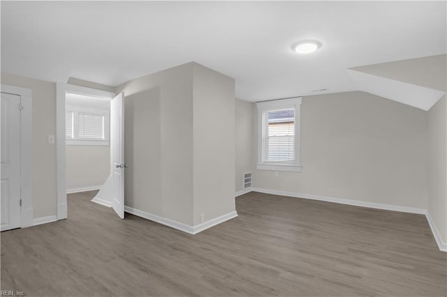 additional living space featuring light hardwood / wood-style floors and vaulted ceiling