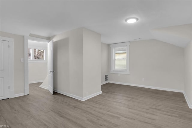 bonus room with plenty of natural light, light hardwood / wood-style floors, and vaulted ceiling