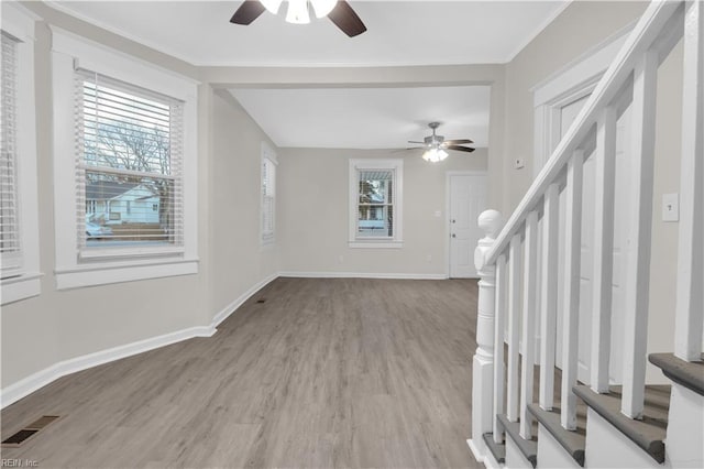 unfurnished living room featuring crown molding, ceiling fan, and light hardwood / wood-style floors