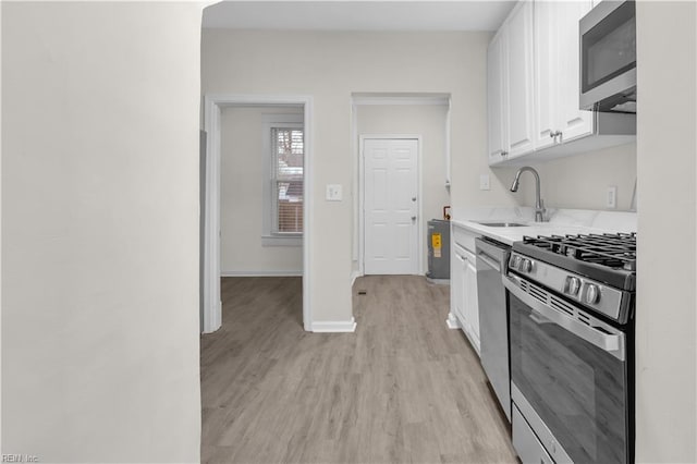 kitchen with white cabinetry, sink, light wood-type flooring, and appliances with stainless steel finishes