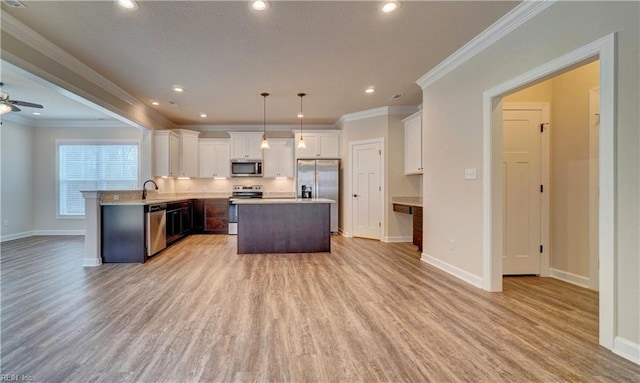 kitchen with appliances with stainless steel finishes, ornamental molding, light hardwood / wood-style floors, white cabinetry, and hanging light fixtures