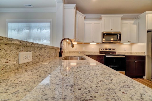 kitchen with light stone counters, ornamental molding, sink, and appliances with stainless steel finishes