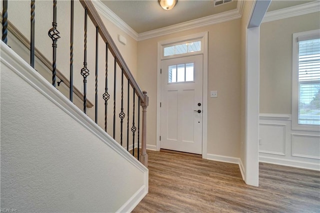 entryway featuring hardwood / wood-style flooring, a healthy amount of sunlight, and ornamental molding