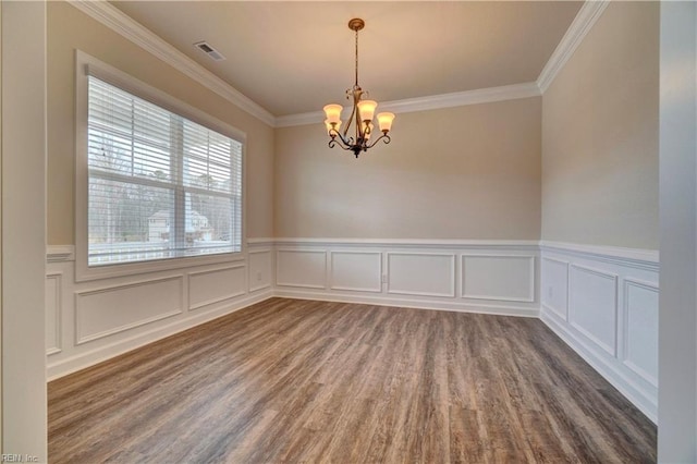 spare room featuring wood-type flooring, ornamental molding, and a chandelier