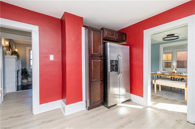 kitchen with a fireplace, stainless steel fridge, and light hardwood / wood-style flooring