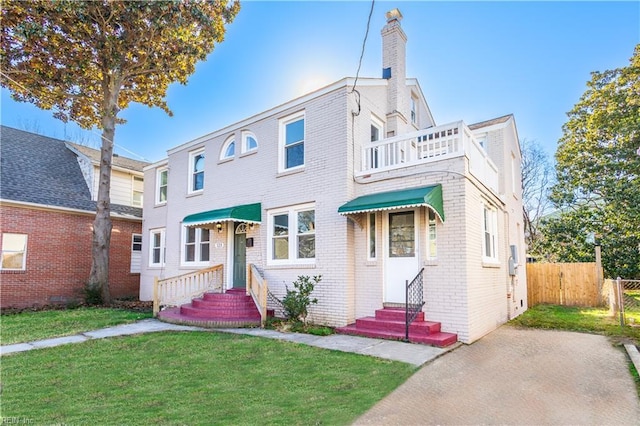 view of front of property featuring a balcony and a front lawn