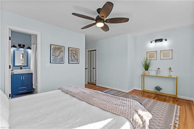 bedroom with hardwood / wood-style flooring, ceiling fan, sink, and connected bathroom