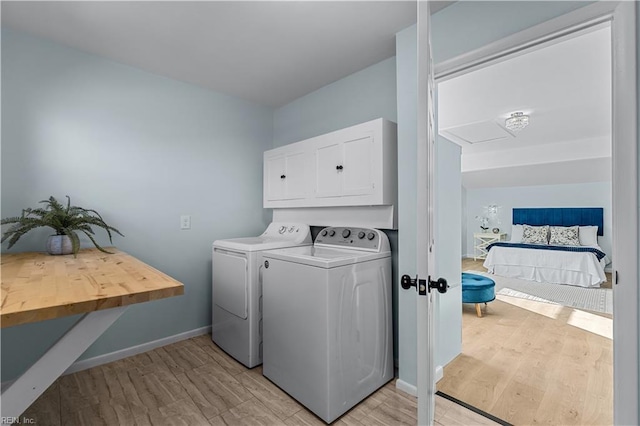 washroom featuring cabinets, washer and clothes dryer, and light hardwood / wood-style floors