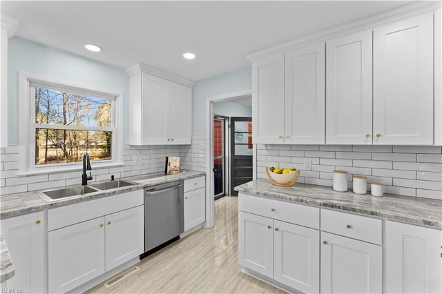 kitchen with tasteful backsplash, light stone counters, stainless steel dishwasher, sink, and white cabinetry