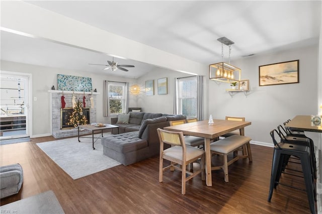 dining room featuring a fireplace, ceiling fan with notable chandelier, and dark hardwood / wood-style floors