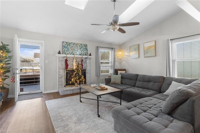 living room featuring lofted ceiling with skylight, hardwood / wood-style floors, a healthy amount of sunlight, and a brick fireplace