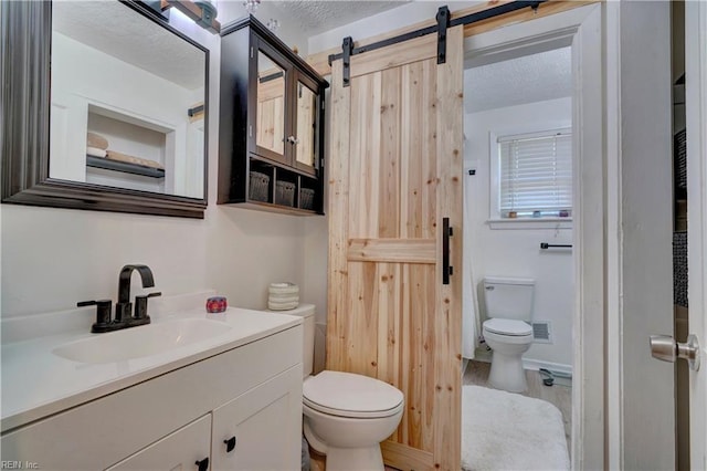 bathroom featuring vanity, a textured ceiling, and toilet