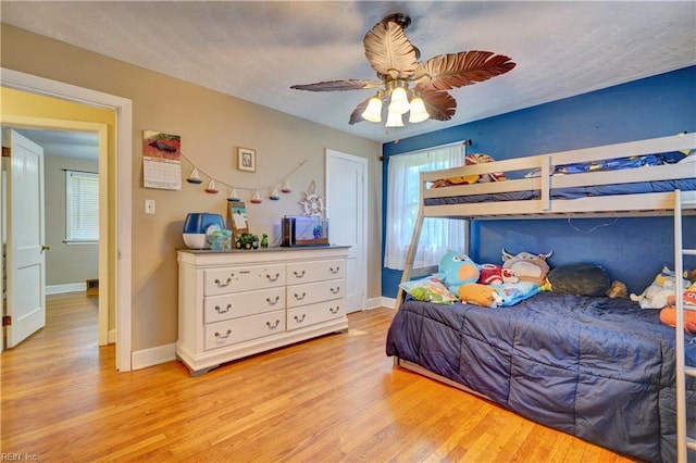 bedroom featuring ceiling fan, light hardwood / wood-style floors, and a textured ceiling