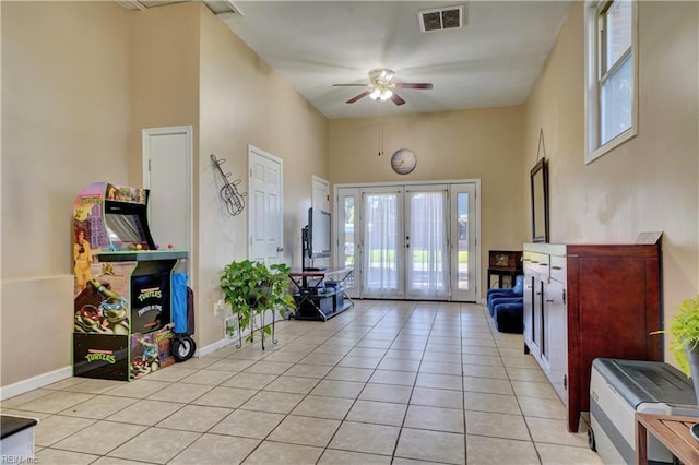 interior space with french doors, a towering ceiling, ceiling fan, and light tile patterned flooring